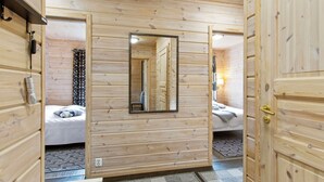 A wooden cabin room with a bed, a mirror, and a door.