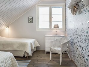A bedroom with a sloped ceiling, a bed, a chair, a dresser, and a window with a view. - Villa akuliina by Interhome (Multia)