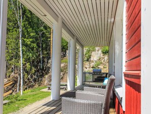 A covered outdoor seating area with a table and chairs, overlooking a natural landscape with trees and a rocky outcrop. - Villa akuliina by Interhome (Multia)