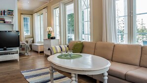 A spacious living room with a large window, a television, a sofa, and a coffee table. - Villa akuliina by Interhome (Multia)