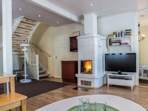 A living room with a fireplace, a television, a bookshelf, and a staircase. - Villa akuliina by Interhome (Multia)
