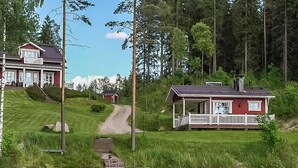 A lakeside cabin with a dock, surrounded by lush greenery and tall trees. - Villa akuliina by Interhome (Multia)