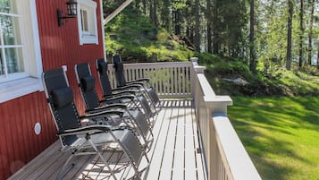 Eine Terrasse mit mehreren Stühlen und einer Brüstung, mit Blick auf ein bewaldetes Gebiet.