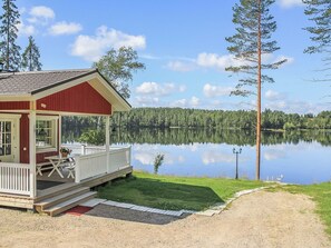A cabin with a deck, a dock, and a view of a calm lake surrounded by trees. - Villa akuliina by Interhome (Multia)