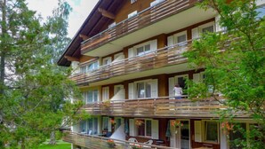 A multi-story hotel with wooden balconies, outdoor seating, and a garden area. - Zur Linde Apt.W by Interhome (Wengen)