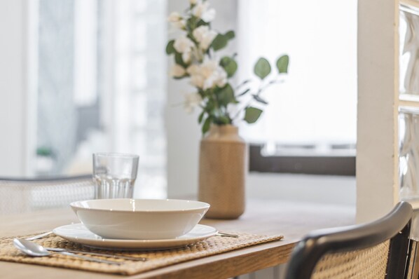 A dining table with a bowl, a glass, and a vase with flowers.
