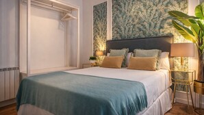 A bedroom with a bed, a nightstand, a lamp, and a plant.