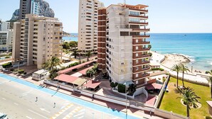 Un hotel moderno de gran altura con varias plantas, vistas a la playa y un estacionamiento con una acera para peatones.