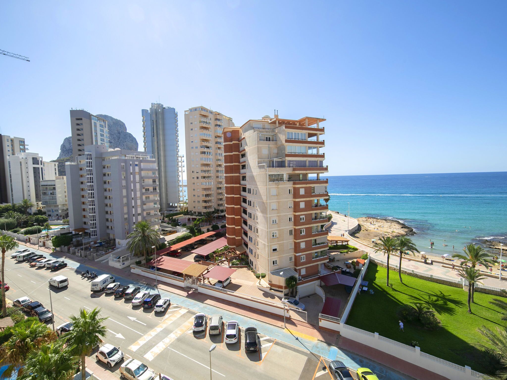Paisagem costeira urbana com edifícios altos, um estacionamento e uma praia.