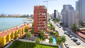 Un hotel de gran altura con varios pisos, piscina y vistas a la ciudad y la costa.