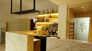 Een moderne bar met een marmeren aanrecht, een wijnrek en een koffieapparaat.