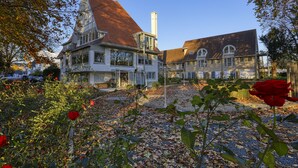 Een groot, historisch huis met een steil dak en een opvallende schoorsteen.