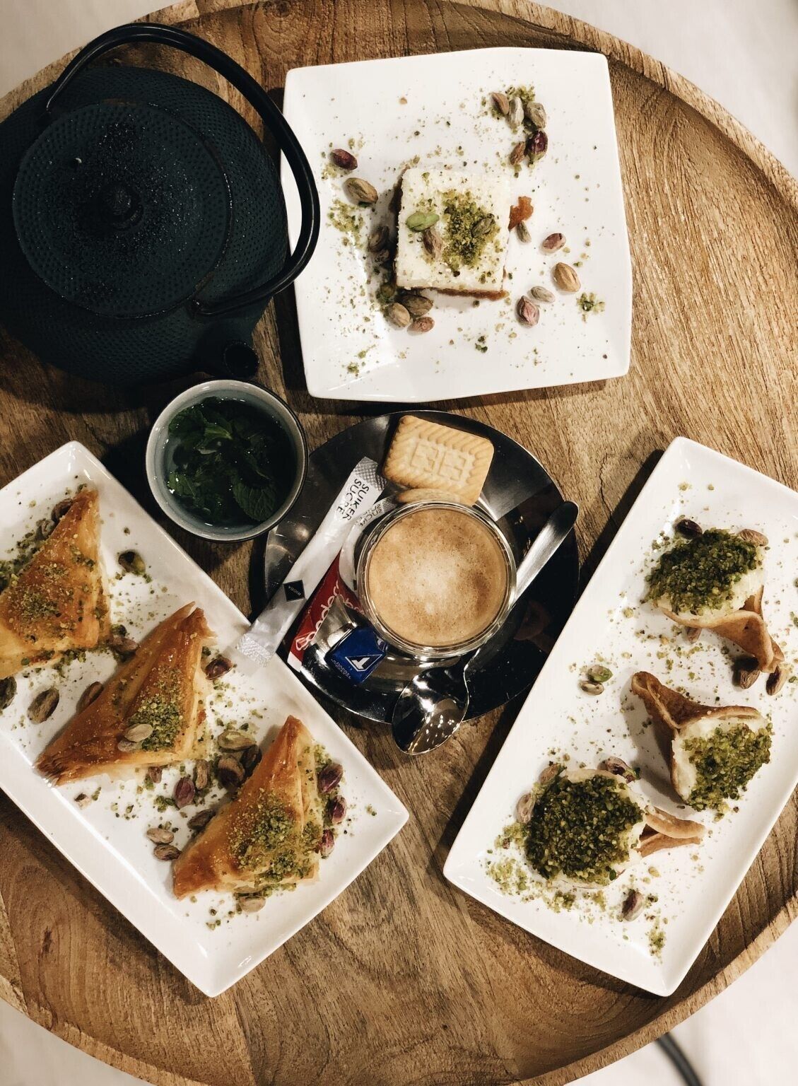 A wooden table with various food items, including pastries and a cup of coffee.