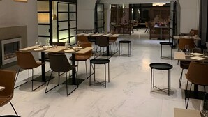 Een moderne eetruimte met marmeren vloeren, eigentijdse meubels en een centrale kroonluchter.