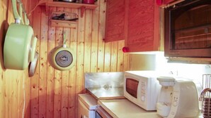Eine kleine Küche mit Holzwänden, einer Mikrowelle, einem Toaster und einem Spülbecken.