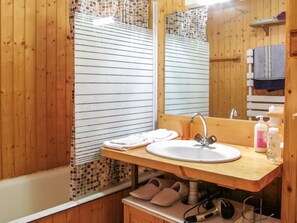 Ein Badezimmer aus Holz mit Waschbecken, Spiegel und Dusche.