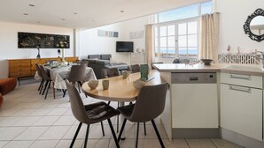 A modern kitchen with a dining area, a sofa, and a TV. - La Plage by Interhome (Dinard)