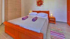 A bedroom with a bed, a nightstand, a wardrobe, and a colorful rug. - Apartment Val by Interhome (Sveti Juraj)