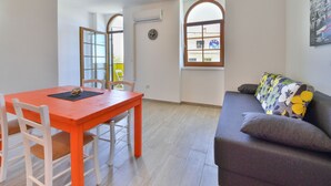 A room with a dining table, chairs, a sofa, and a window with a view. - Apartment Val by Interhome (Sveti Juraj)
