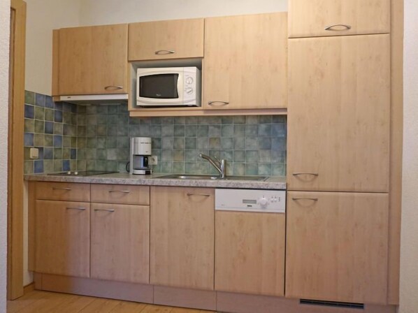 A kitchen with wooden cabinets, a microwave, a coffee maker, and a dishwasher.