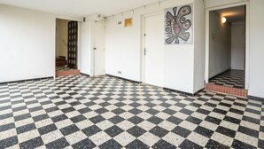 A hallway with a checkered floor, white walls, and a door with a decorative pattern. - Les Amandiers by Interhome (Canet-Plage)