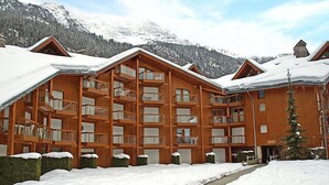 A wooden lodge with multiple balconies and a snow-covered landscape.