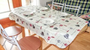A dining table set with plates, glasses, and cutlery, covered with a tablecloth featuring food and drink illustrations.