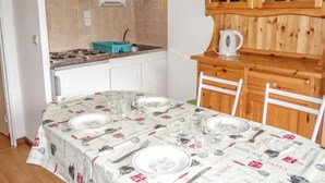 A compact kitchen with white cabinets, a wooden cabinet with glass doors, and a dining table set for four.
