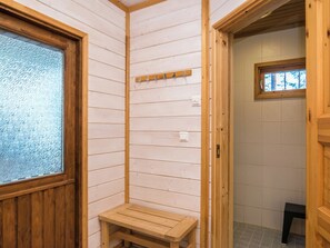 Un interior de madera con un banco, una mesa pequeña y un ventanal.