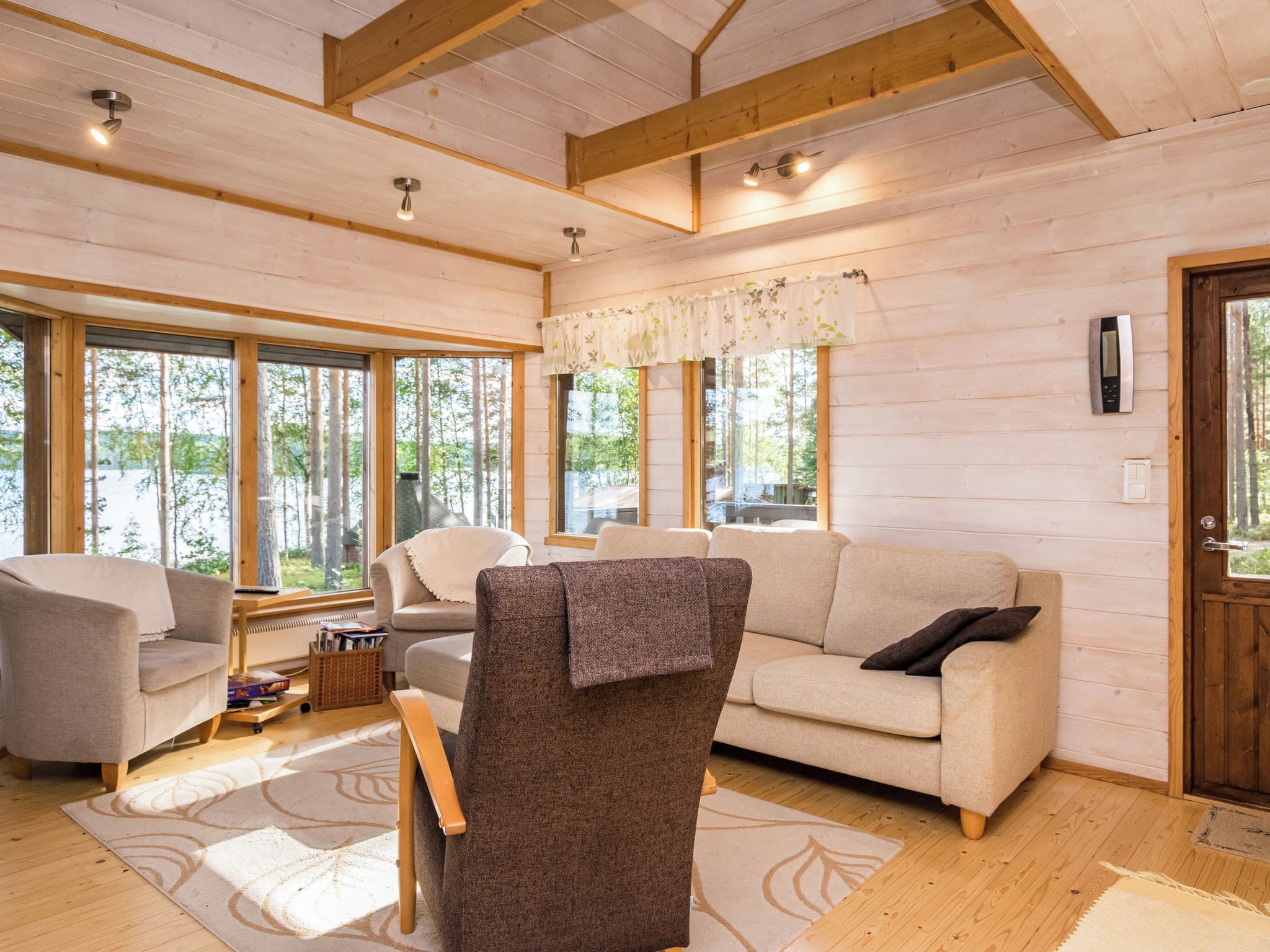 Ein gemütliches Interieur mit Holzbalkendecke, großen Fenstern und einer Sofagarnitur.