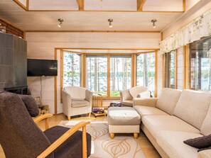 Een moderne woonkamer met een grote bank, twee fauteuils, een televisie en een open haard.