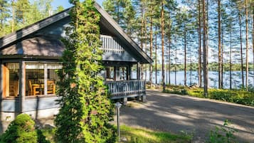 Eine Hütte mit Veranda, umgeben von Bäumen und einem See.