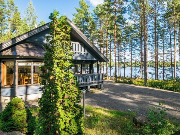 A cabin with a porch, surrounded by trees and a lake. - Kuvalanranta by Interhome (Mäntyharju)