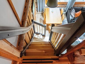 Una escalera de madera con barandillas de metal que lleva a una habitación con una mesa y sillas.