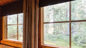 Una cabaña con amplios ventanales que ofrecen vistas a un bosque.
