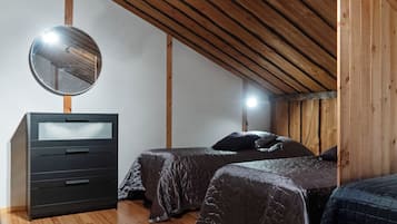 A bedroom with two beds, a dresser, a mirror, and wooden beams on the ceiling.