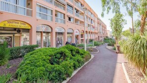 Ein mehrstöckiges Hotel mit Balkonen, einem zentralen Innenhof und verschiedenen Geschäften im Erdgeschoss.