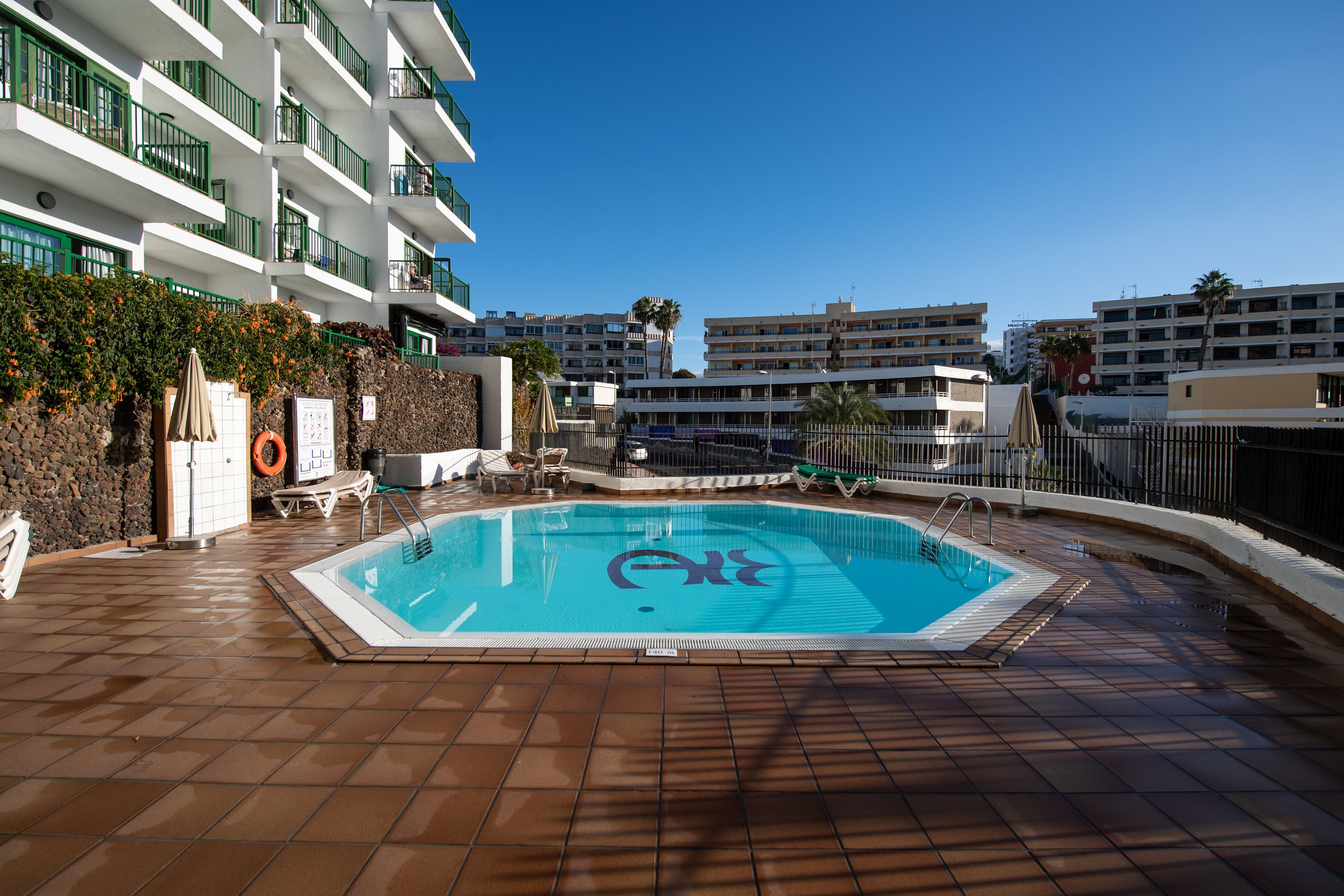 Een buitenzwembad, ligstoelen bij het zwembad