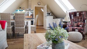 A loft-style room with a dining area, kitchenette, and seating area.