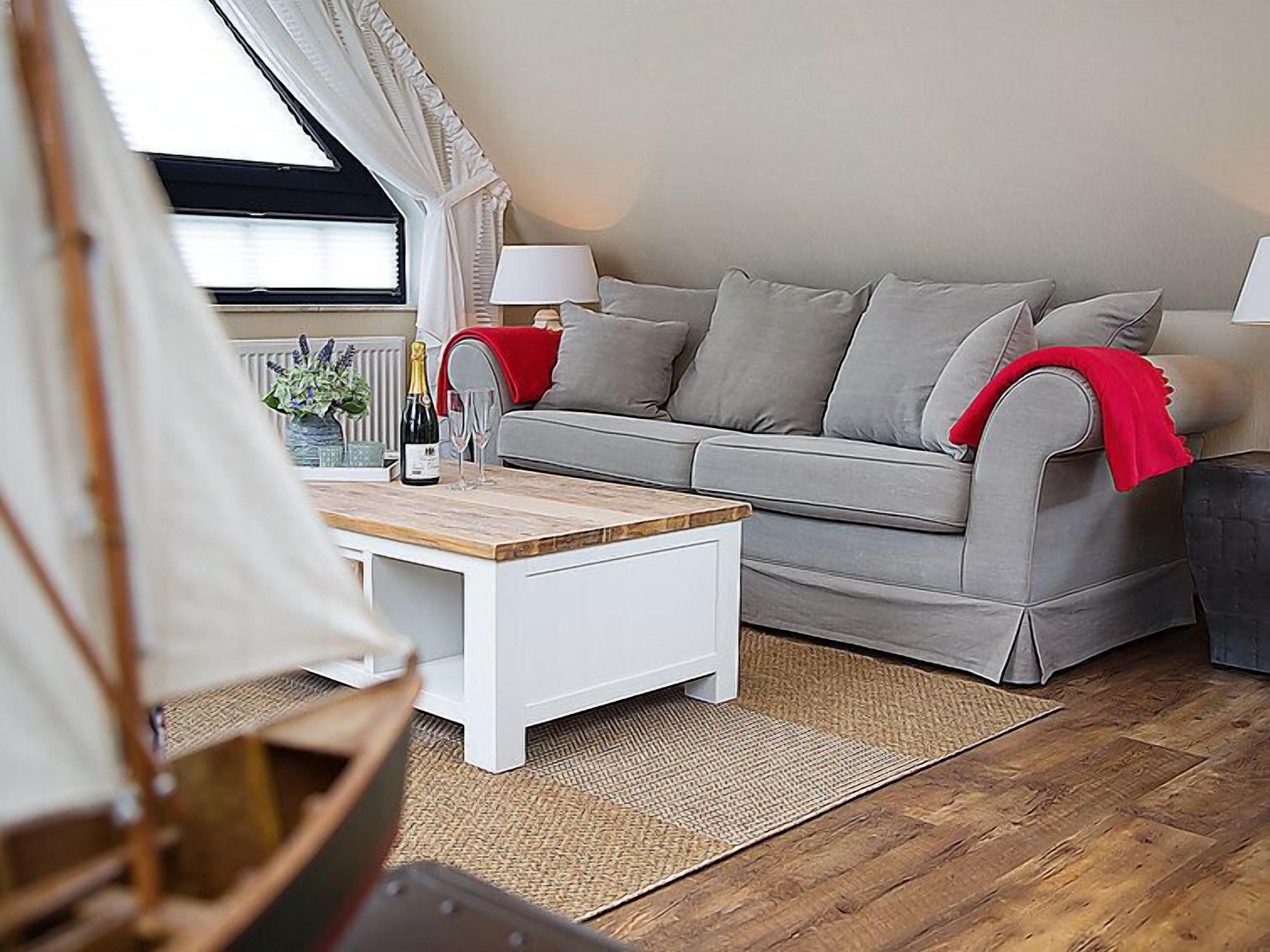A cozy living room with a grey sofa, a white coffee table, and a wooden floor.