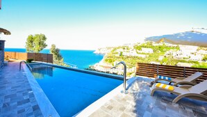 An infinity pool with a clear view of the sea and a hillside with buildings. - Sea Front Panorama Villa Private Pool (Malevizi)