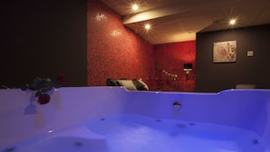 A spa area with a hot tub, a red patterned wall, and a painting of a heart. - Motel Los Abedules (Oviedo)