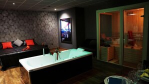 A modern spa room with a black leather sofa, a large bathtub, and a wooden cabinet. - Motel Los Abedules (Oviedo)