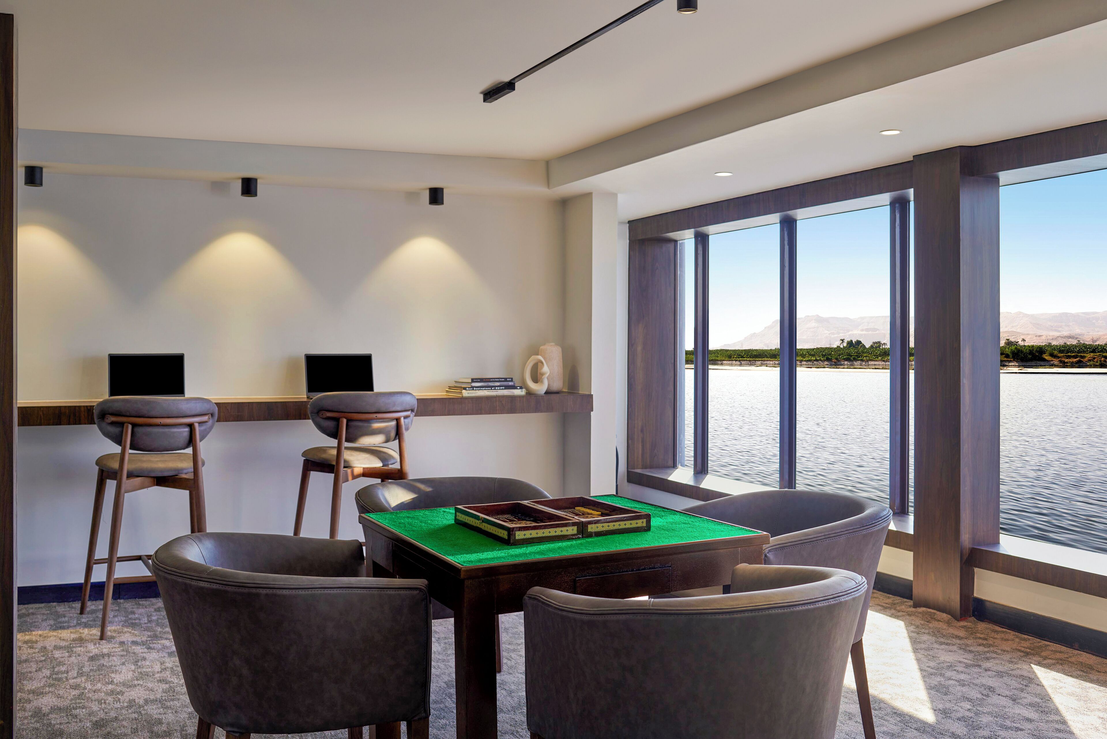 Quarto moderno com vista para a piscina, com uma mesa, cadeiras, estante e uma janela grande.