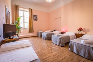 A hotel room with four beds, a television, a plant, and a window with curtains. - Rooms77 Florence (Florence)