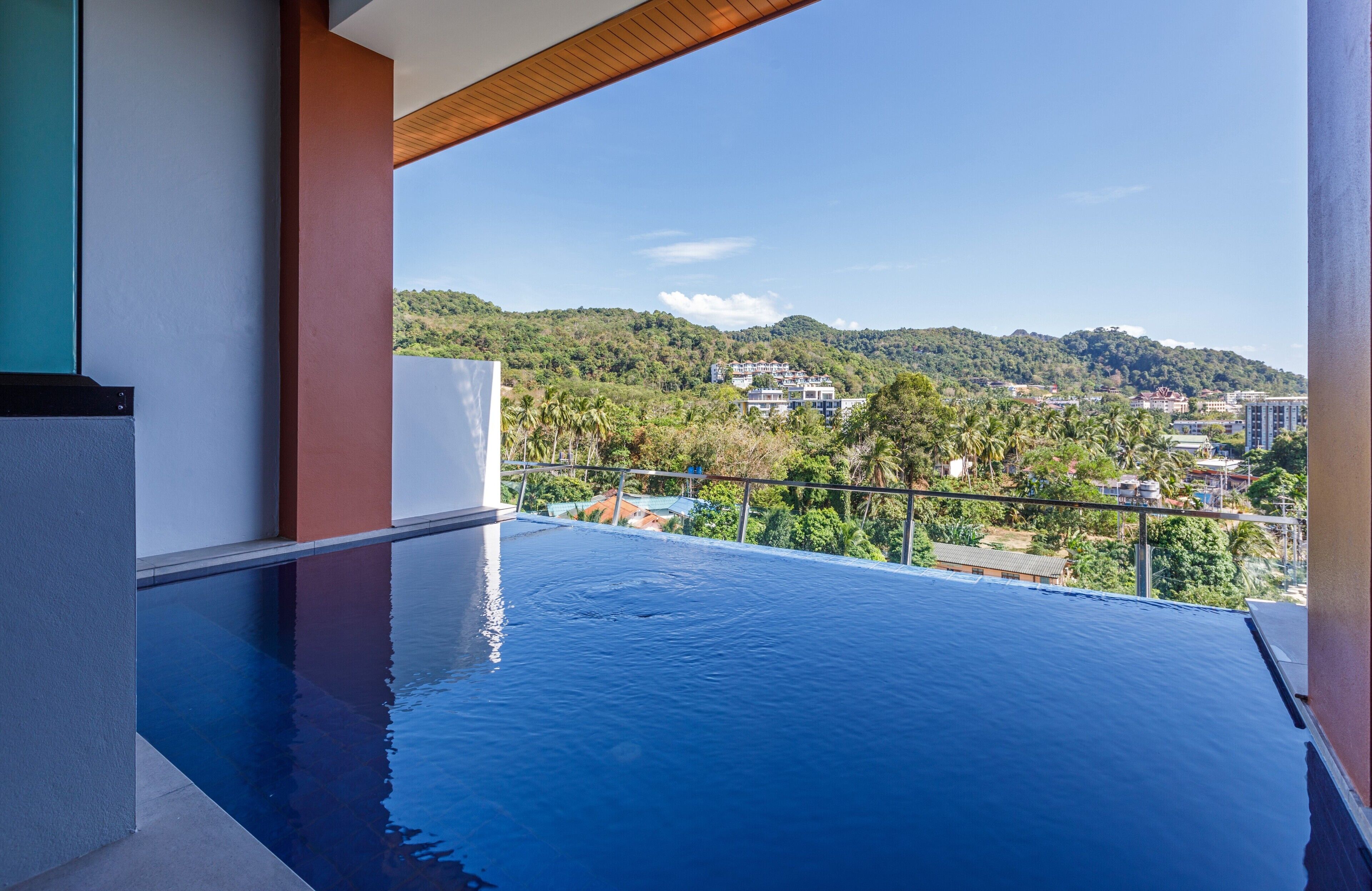 Uma piscina infinita moderna, com vista desobstruída para uma encosta e edifícios ao fundo.