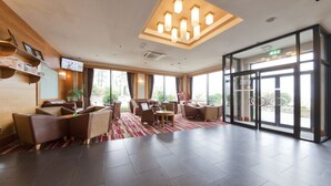 A modern lobby with a seating area, a large window, and a door with a glass panel. - Upton Court Holiday Cottages (Kilmuckridge)