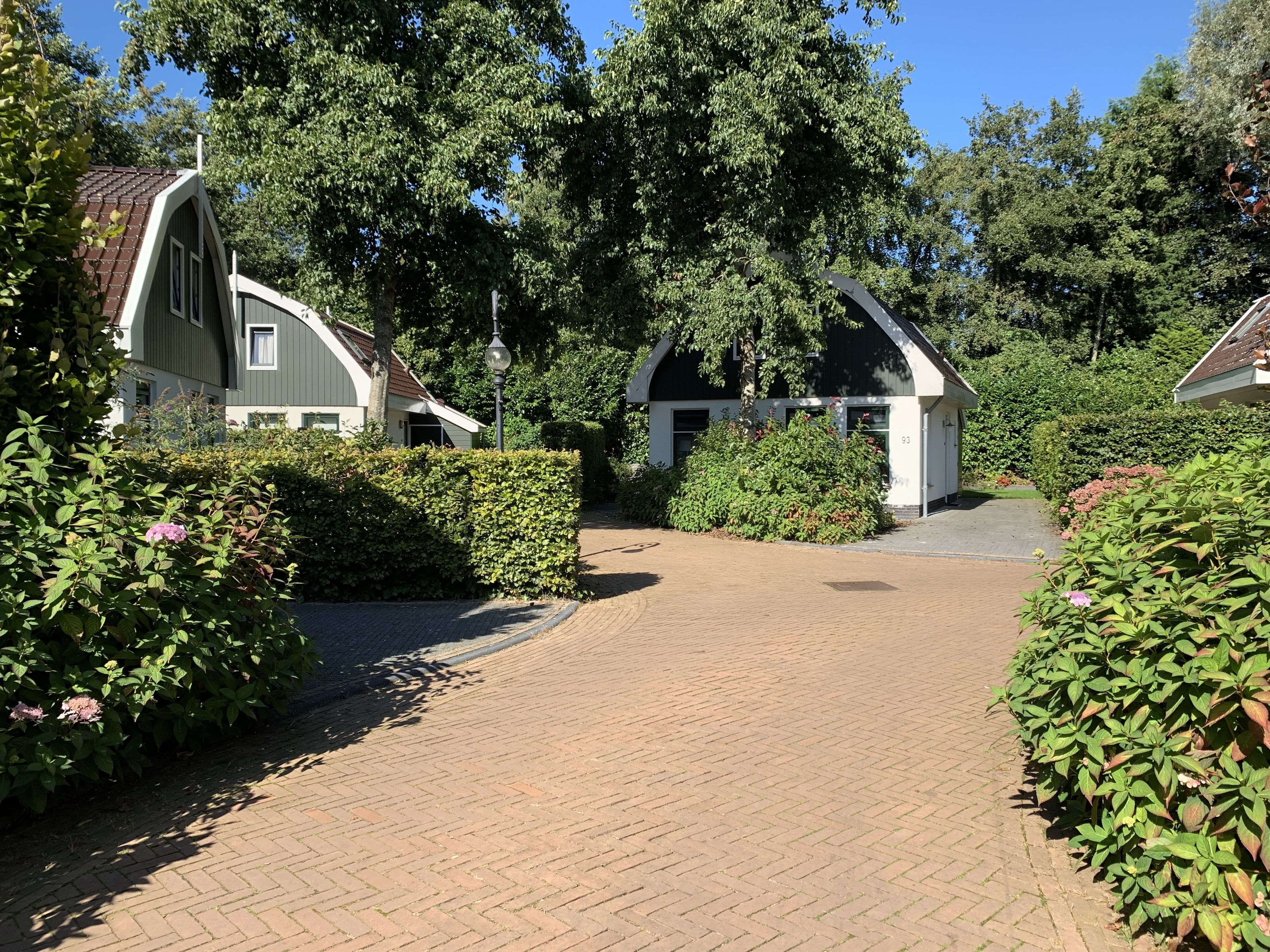 A paved pathway leading to a building with a sloped roof and a small attached structure.