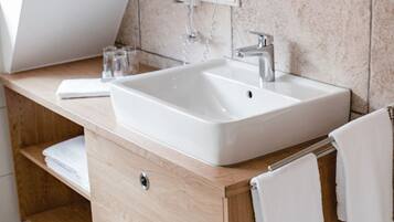 Un baño moderno con lavamanos independiente, tocador de madera y un espejo grande.