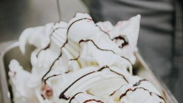 A tray of ice cream with whipped cream and chocolate drizzle.